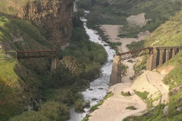 پل قطاری زنگ‌زده و ویران‌شده در اردن؛ رودخانه‌ای در زیر آن جاری است.
