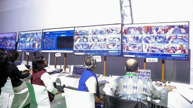 ২০২৫ সালের দিল্লি বিধানসভা নির্বাচনে নির্বাচনী কর্মকর্তারা ওয়েবক্যাস্টিং কন্ট্রোল রুমে পোলিং বুথ তদারকি করছেন একাধিক স্ক্রিনের মাধ্যমে — ফাইল ছবি।