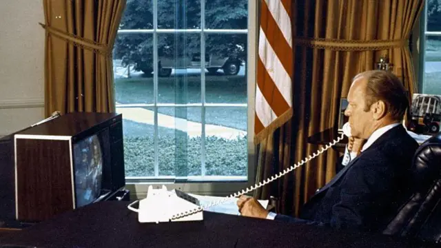 1975年7月17日,美國總統福特坐在白宮橢圓形辦公室的辦公桌前,透過電話與「阿波羅號」上的太空人通話。他一邊講電話,一邊注視著面前的監視器畫面。