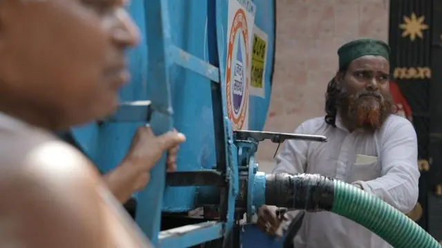 टैंकर से पानी भरते लोगों की तस्वीर