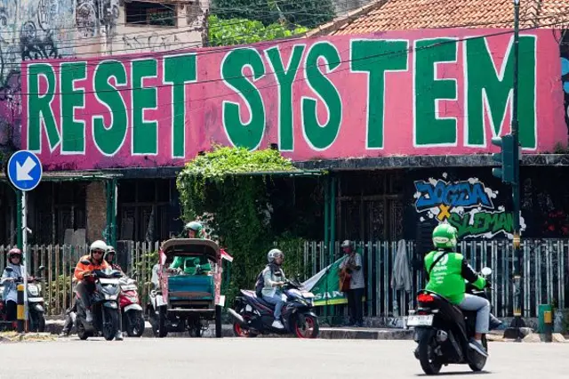 Grafiti yang bertuliskan "Reset System", yang dilukis oleh seniman lokal selama protes baru-baru ini, terlihat melewati lalu lintas di Yogyakarta pada 3 September 2025 