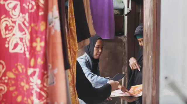 Yuni Sri Rahayu membagikan brosur kampanye ke warga.