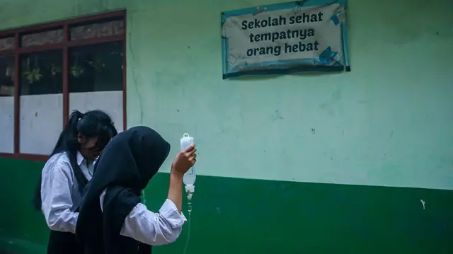 Seorang siswa SMK berjalan sambil memakai infus karena keracunan makanan usai mengonsumsi makanan sekolah gratis di SMPN 1 Cisarua, Kabupaten Bandung Barat, Jawa Barat, pada 15 Oktober 2025.