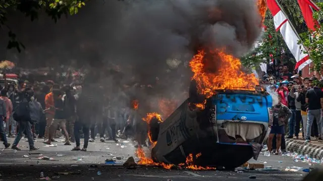 Massa membakar mobil polisi saat berunjuk rasa di Kabupaten Pati, Jawa Tengah, Rabu (13/08).