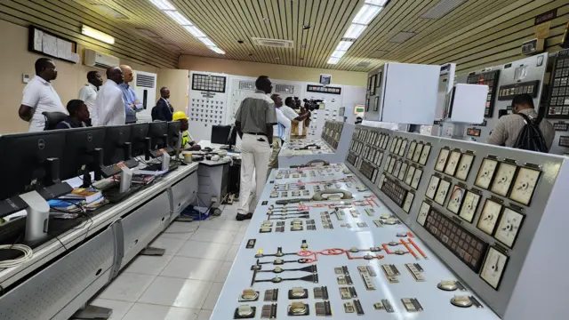 Des travailleurs se tiennent dans une salle de contrôle pour les barrages existants d'Inga.