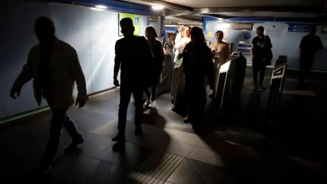 Sejumlah penumpang kereta keluar dari stasiun dalam kondisi gelap.