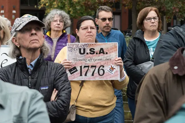 Женщина держит в руках плакат 