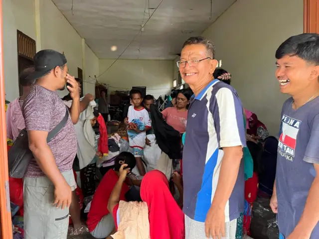 Robin Sitompul di garasinya sedang membagikan bantuan pakaian kepada para pengungsi.