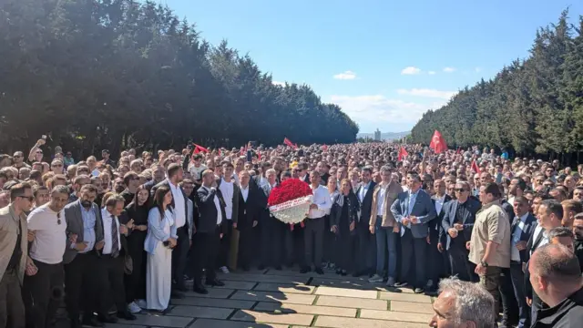 Kalabalığın önünde özgür Özel ve Mansur Yavaş bir çelenk taşıyor