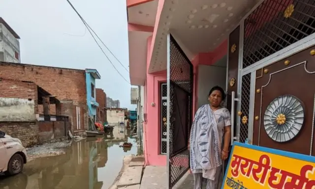 ਆਪਣੇ ਘਰ ਦੇ ਬਾਹਰ ਖੜ੍ਹੇ ਪਦਮਾਵਤੀ, ਸਾਹਮਣੇ ਗਲੀ ਵਿੱਚ ਪਾਣੀ ਖੜ੍ਹਾ ਹੈ