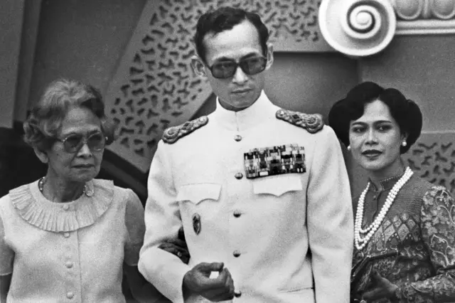 พระบาทสมเด็จพระบรมชนกาธิเบศร มหาภูมิพลอดุลยเดชมหาราชฯ ประทับยืนเคียงข้าง สมเด็จพระศรีนครินทราบรมราชชนนี พระราชมารดา และสมเด็จพระนางเจ้าสิริกิติ์ พระบรมราชชนนีพันปีหลวง ถ่ายเมื่อ 1 มกราคม 2525