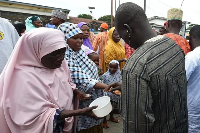 Un fidèles musulman donne des pièces de monnaie en guise d'aumone à des femmes réunies devant la mosquée syrienne de Lagos. 