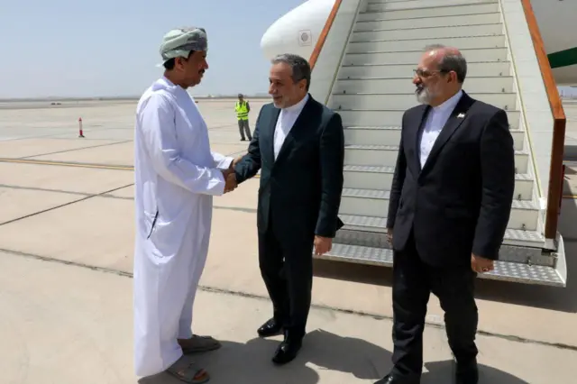 مسؤول عُماني لم يُكشف عن هويته يستقبل وزير الخارجية الإيراني عباس عراقجي لدى وصوله إلى مسقط، عُمان، في 11 مايو/أيار 2025.