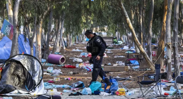 Policial uniformizado andando em meio a destroços do ataque de 7 de outubro.