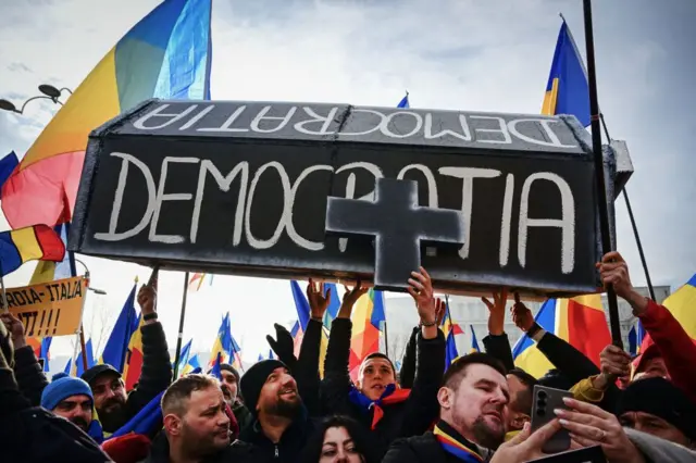 Люди несут гроб с надписью “Демократия” на румынском языке