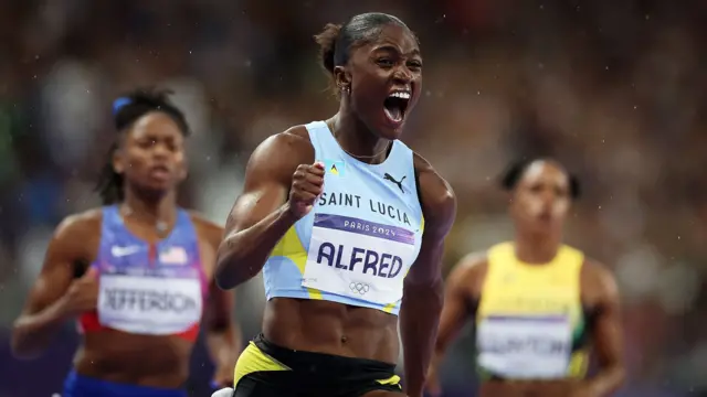 Julien Alfred celebrates after crossing the finishing line in a race