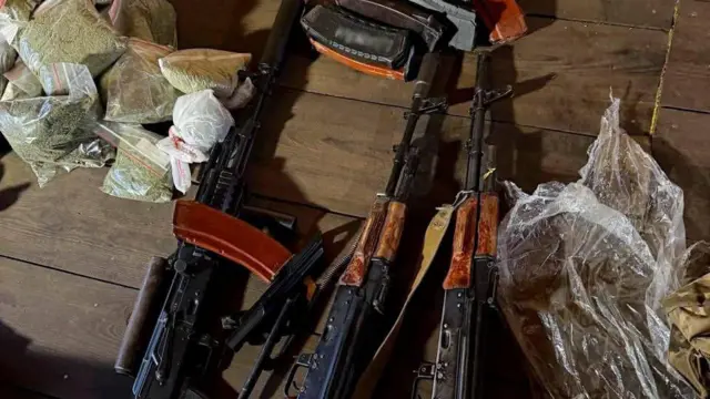 Кілька автоматів разом із пакетами з невідомою речовиною лежать на столі