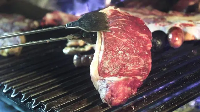 Carne sendo virada enquanto assabonusbetanochurrasqueira