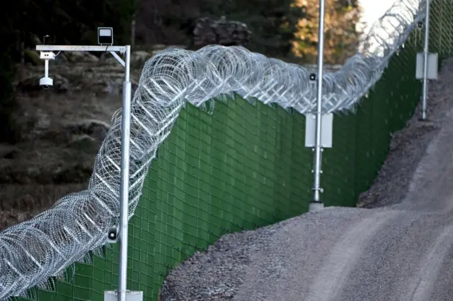 Una valla verde, con cámaras de seguridad y concertina de alambre de navajas a lo largo de la frontera entre Finlandia y Rusia.
