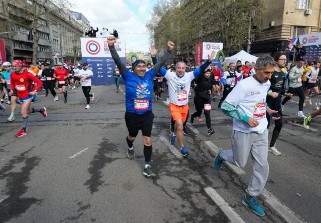 Ljudi gestikuliraju dignutih ruku na početku maratona