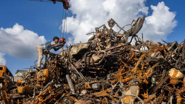 नयाँ बानेश्वरस्थित संसद् भवनमा थुपारिएको जलाइएका मोटरसाइकलहरू। सेतो र नीलो रङ्गको जर्सी लगाएका एक जना कामदार उक्त भग्नावशेषमाथि उभिएर कवाडलाई समेट्दै गरेको देखिन्छन्