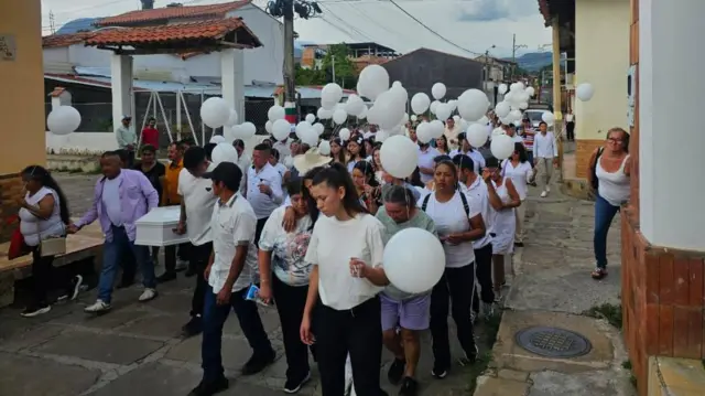 Un grupo de niños y niñas con camisetas blancas y globos blancos