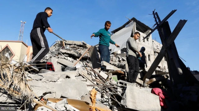 Palestinians inspect the damage at the site of Israeli strikes on houses, amid the ongoing conflict between Israel and the Palestinian Islamist group Hamas, in Khan Younis in the southern Gaza Strip, December 10, 2023
