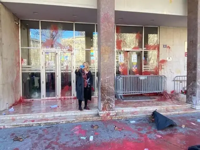 Žena ispred zgrade skupštine Grada Beograda koju je desetine ljudi prethodno gađalo jajima i kesicama sa crvenom bojom