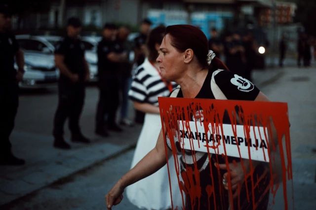 žena sa transparentom protiv žandarmerije