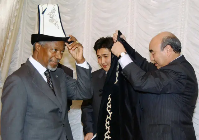 Кофи Аннанга калпак жана чапан кийгизип сыйлап жатат