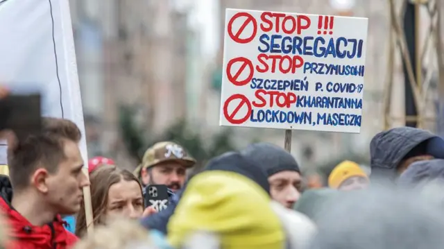Zdjęcie przedstawia protestujących z hasłami sprzeciwiającymi się programom szczepień przeciwko COVID-19 w Gdańsku, 29 stycznia 2022 r., zorganizowanymi przez skrajnie prawicową partię Konfederacja.
