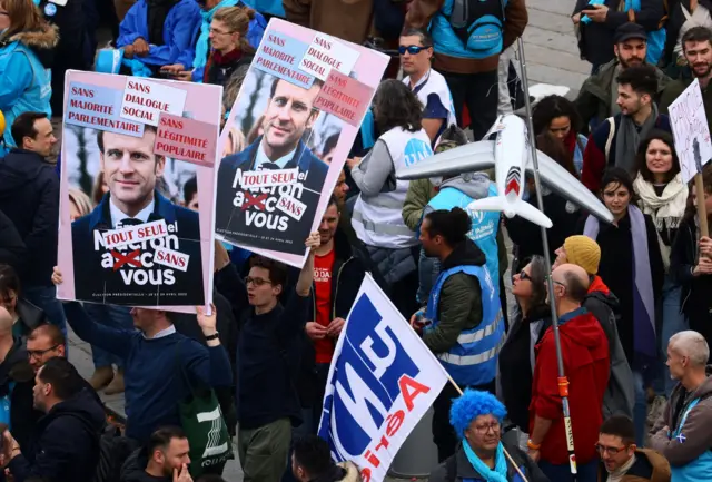 Participantes de protesto seguram cartazes com um retrato do presidente francês Emmanuel Macron durante uma manifestação contra a reforma da previdência do governo francês, em Paris, França, 23 de março de 2023