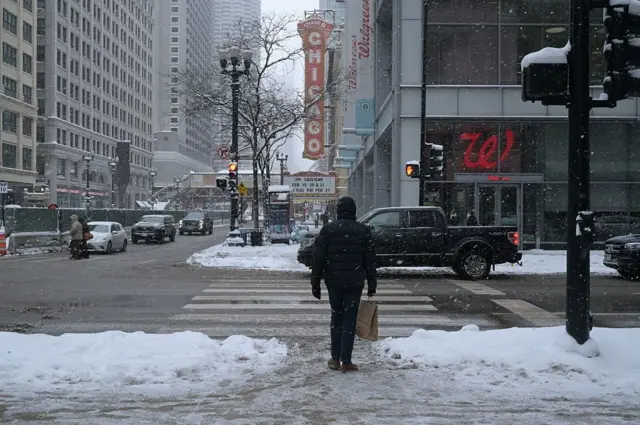 Chicago'da karla kaplı sokakta karşıya geçmeye çalışan bir kişi.