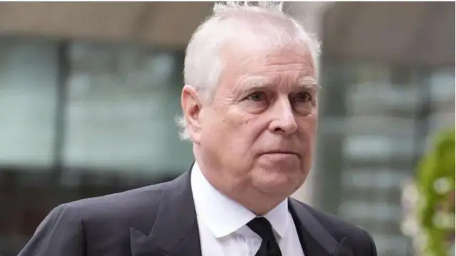 Andrew, ninu aworan akọkọ wọ asọ Kootu alawọ eeru, o wọ shaati alawọ funfun sabẹ kootu naa, o de tai alawọ dudu, ewu si ti gba gbogbo ori rẹ tan.