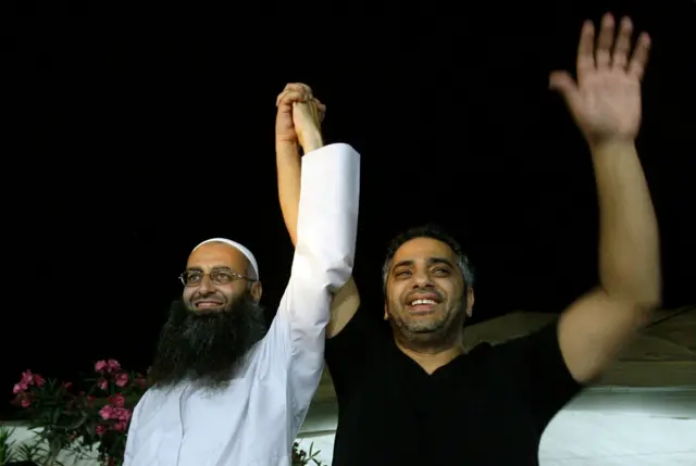 رجل الدين السلفي اللبناني الشيخ أحمد الأسير (يسار) يمسك بيد المغني اللبناني فضل شاكر خلال أمسية صغيرة أنشد فيها شاكر أناشيد دينية في مدينة صيدا جنوبي لبنان، في 27 يوليو/تموز 2012.