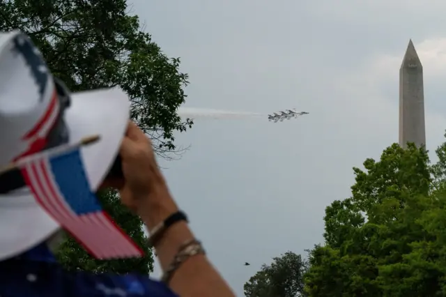 ชายคนหนึ่งกำลังชมเครื่องบินรบ F-16 ของทีม Thunderbirds แห่งกองทัพอากาศสหรัฐฯ บินโฉบเหนือเนชันแนล มอลล์ ในงานเฉลิมฉลองครบรอบ 250 ปีแห่งการประกาศอิสรภาพของสหรัฐฯ
