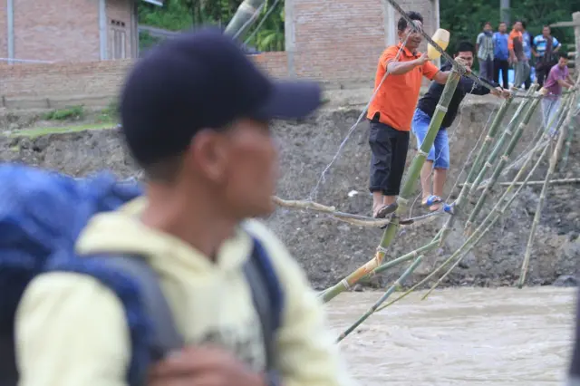 Sejumlah warga korban bencana yang terisolir melintasi Daerah Aliran Sungai (DAS) lewat jembatan tali darurat penghubung Desa Uyem Beriring dan Desa Pasir, Kecamatan Tripe Jaya, Gayo Lues, Aceh, Sabtu (20/12/2025).