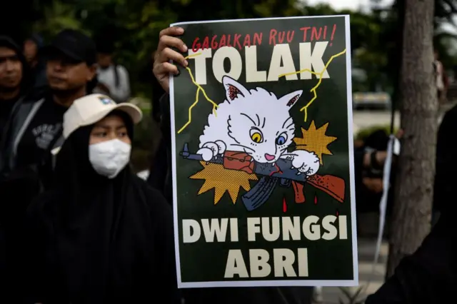 Sejumlah demonstran membentangkan spanduk selama unjuk rasa menentang revisi UU TNI pada 24 Maret 2025 di Surabaya.