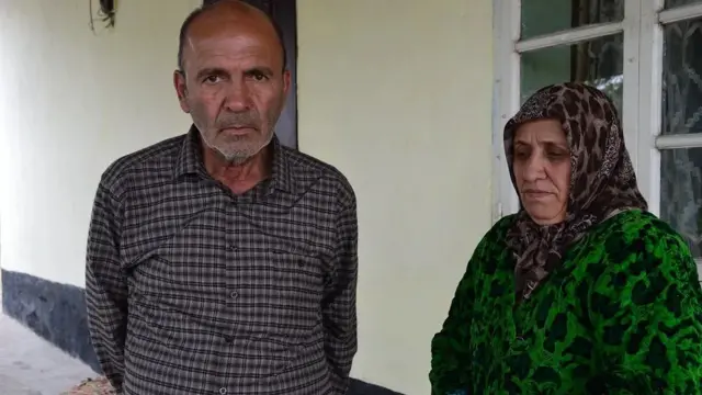 Dalerjon Mirzoyev’s parents, Barot and Gulrakat, pictured with sad expressions outside a building with light coloured walls
