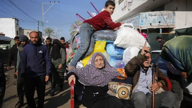 Palestinian citizens carrying their belongings leave their homes in Al-Maghazi refugee camp to seek safer places in the city as Israeli attacks continue in Deir al-Balah, Gaza on 4 January 2024.