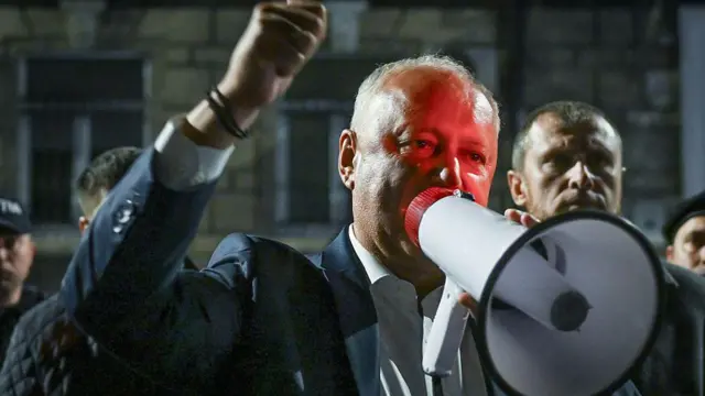 Игорь Додон говорит в мегафон с поднятым в воздух кулаком во время акции протеста у здания ЦИК в Кишиневе.