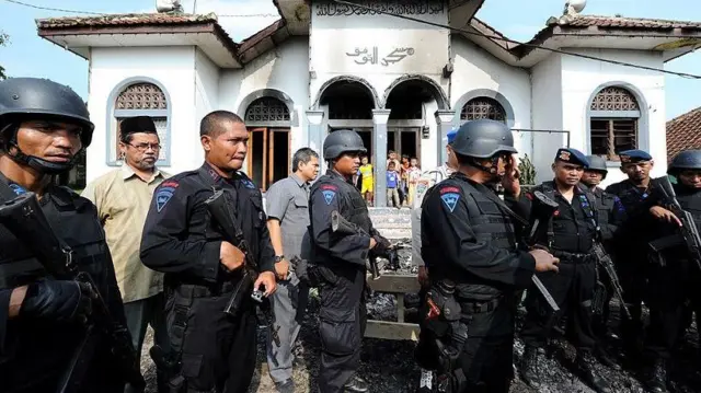 Polisi Brimob berjaga di depan masjid yang rusak di Desa Cisalada, Bogor, pada tanggal 2 Oktober 2010, setelah sekelompok orang menyerang desa tempat tinggal pengikut Ahmadiyah, membakar masjid, rumah dan kendaraan.