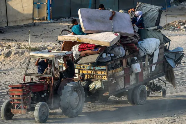 جرار يسحب عربةً تحمل أشخاصاً وأمتعتهم أثناء إجلائهم جنوباً من مدينة غزة في 2 سبتمبر/أيلول 2025. 