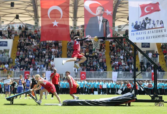 Futbol stadyumundaki gösteride smaç atan bir öğrenci ve izleyiciler. 