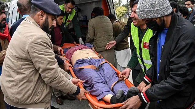 Люди несут раненого мужчину в больницу после взрыва в мечети в Исламабаде