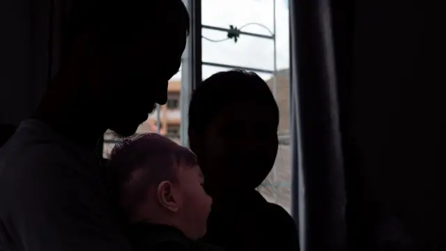 رجل وزوجته في الظل لإخفاء هويتهما وبينهما طفل