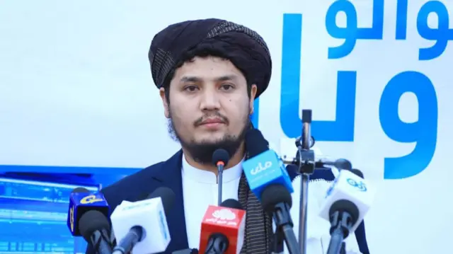 د طالبانو حکومت د کورنیو چارو وزارت ویاند عبدالمتین قانع رسنیو ته خبرې کوي او مخ ته یې د ګڼو رسنیو مایکونه ایښي دي.