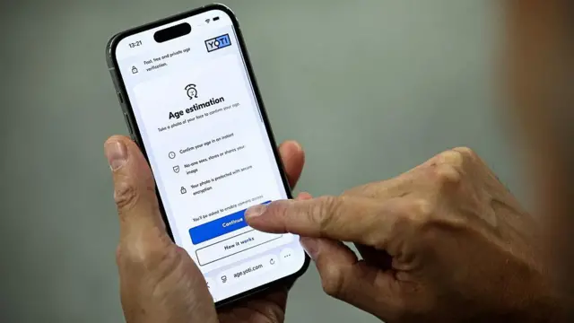 Un hombre sostiene un teléfono que muestra cómo realizar una verificación de estimación de edad de la empresa Yoti