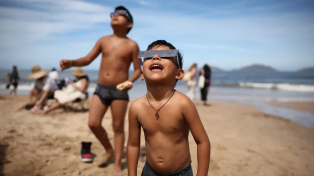 Children dey watch am on di beach for Mazatlan, Mexico, di first place to experience di eclipse