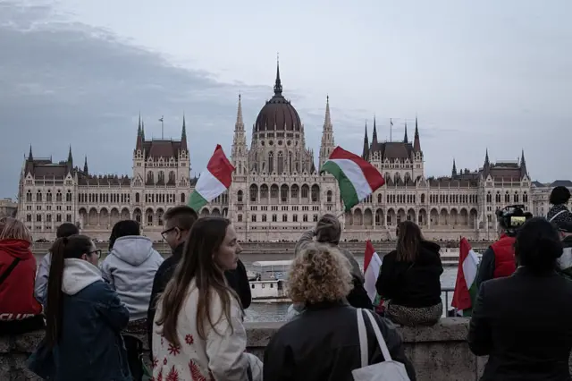 Люди тримають угорські прапори перед парламентом посеред натовпу під час зібрання опозиційної партії "Тиса" з нагоди результатів парламентських виборів у Будапешті, Угорщина, 12 квітня 2026 року.